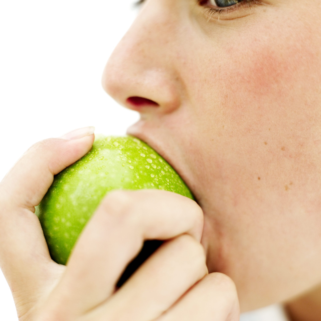 Teen Girl (15-17) Biting into a Green Apple --- Image by © Royalty-Free/Corbis
